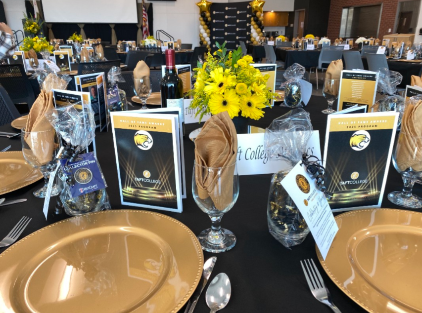 Table set up for Hall of Fame ceremony. It includes plates, cups and a program detailing the events proceedings.